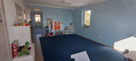 Sala z granatowym dywanem, regałem z klockami i zabawkami